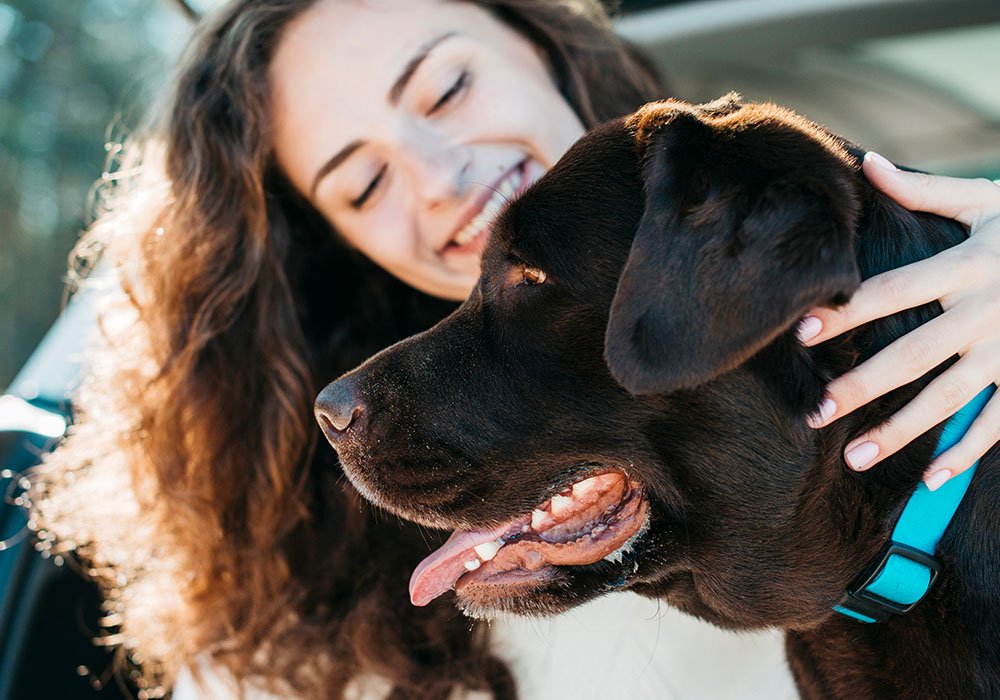 Tutora feliz e sorrindo segurando seu cão